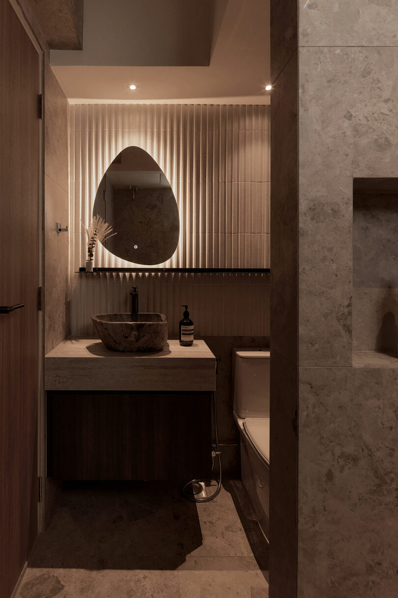 view into dark modern bathroom with back-lit mirror