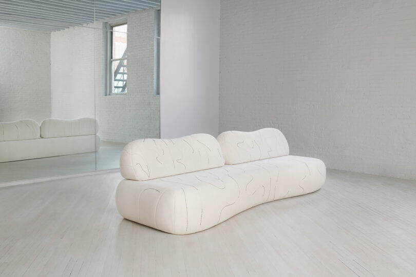 A sofa with line work in an open white room.