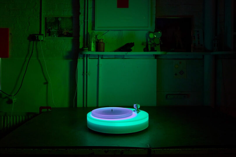 Brian Eno's Turntable II on a table glowing green and violet in a green light illuminated room.