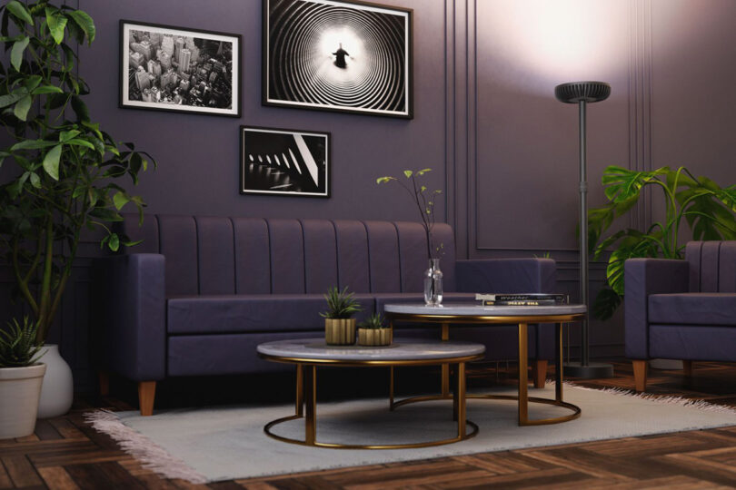 Render of living room with purple sofa and circular coffee tables, houseplants, standing desk and computer with Brighter floor lamp illuminated in the corner.