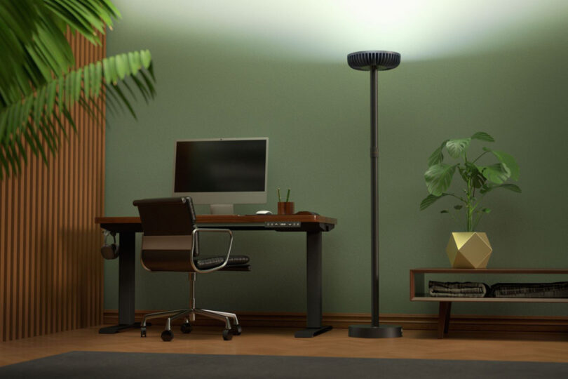 Render of a home office with green walls, houseplants, standing desk and computer with Brighter floor lamp to the right.