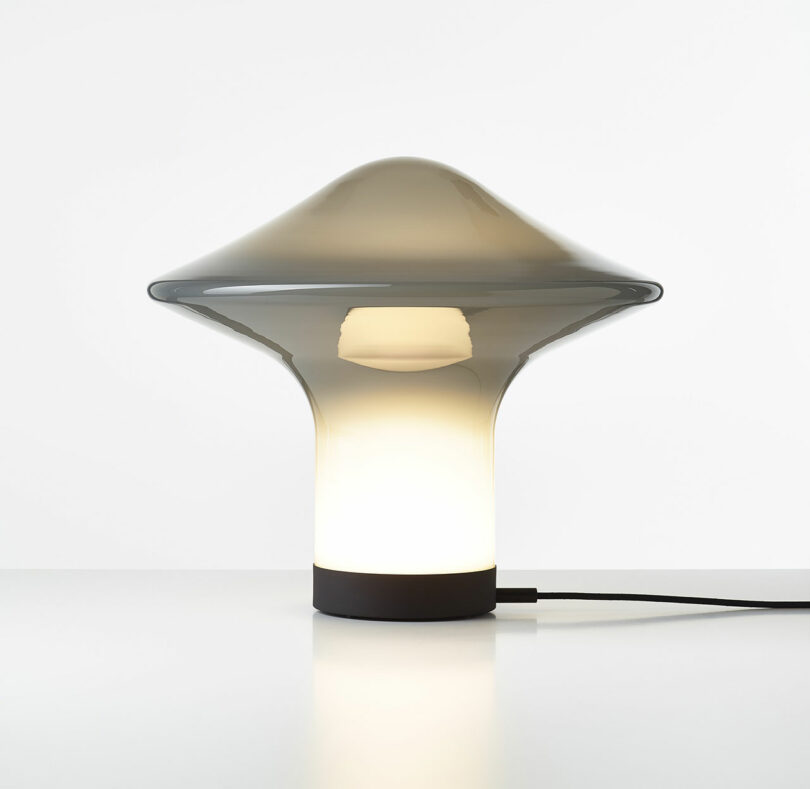 gray opal glass lamp shaped like a spinning top with light on