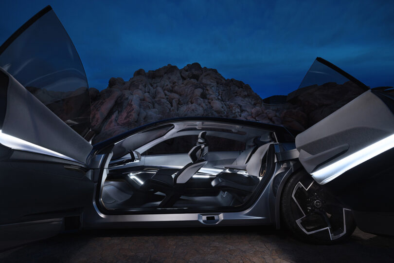 Side driver's side view of the Chrysler Halcyon Concept with doors open against an evening desert backdrop.