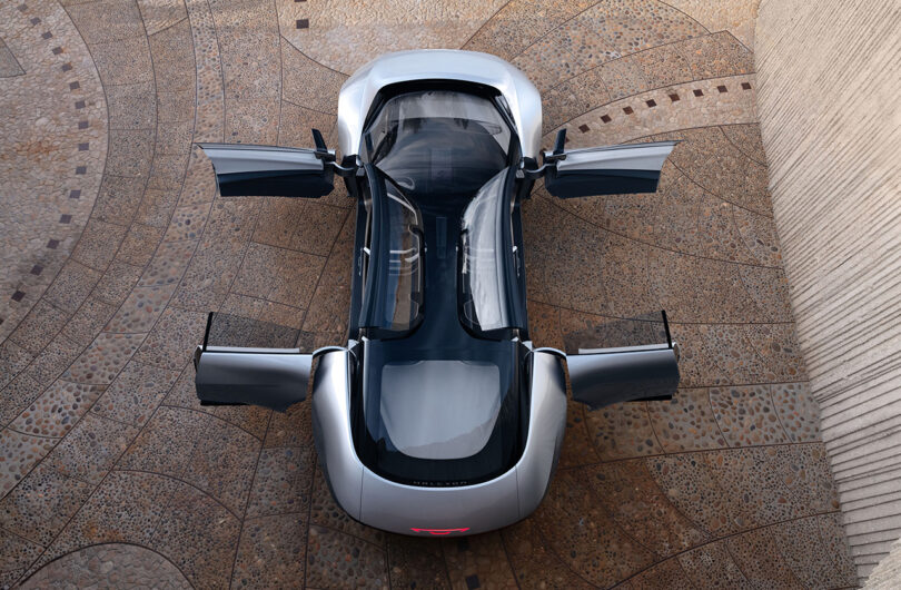 Top overhead view of the Chrysler Halcyon Concept with all six doors open parked in front of a modern architectural residence with unique circular stone embellished driveway.