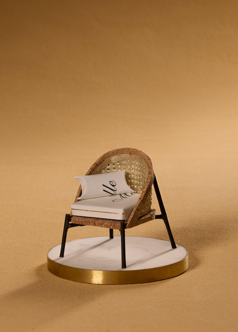 A miniature chair made from champagne bottle packaging presented on a tiny plinth.