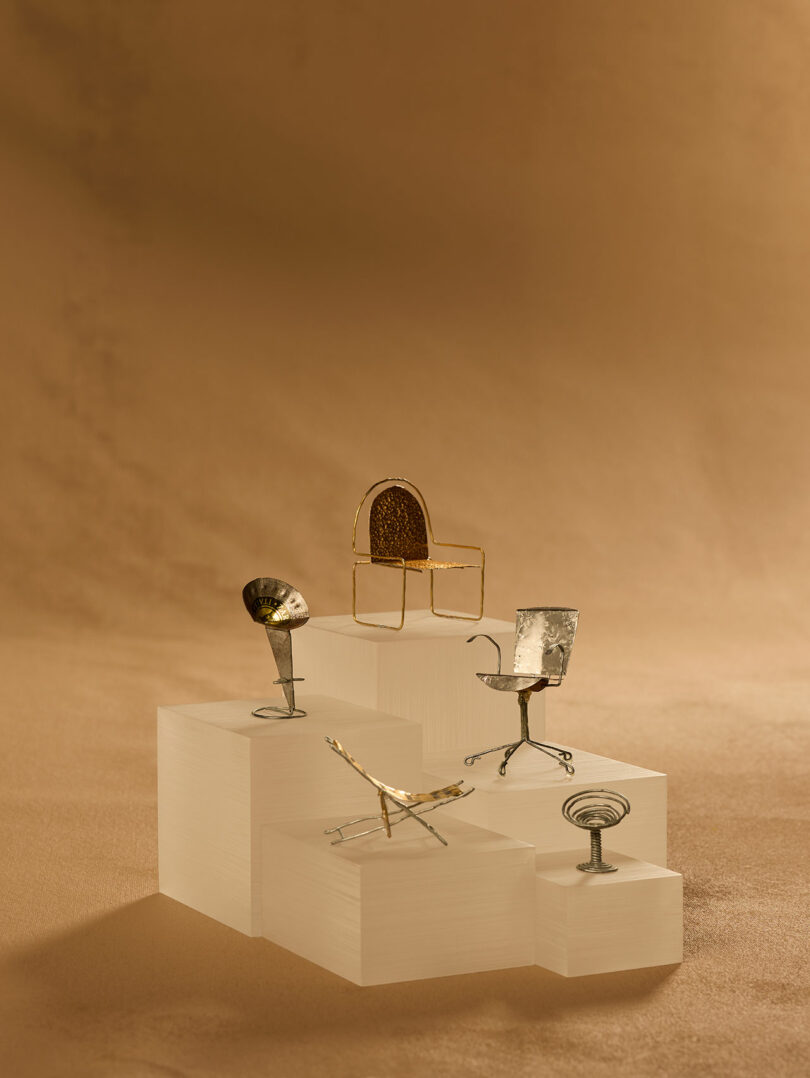 A roundup of miniature chairs made from champagne bottle packaging presented on tiny pedestals.