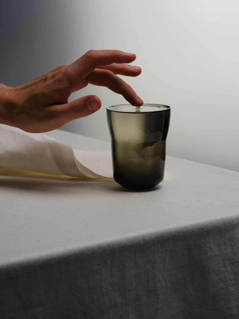 a hand touching the surface of the water in a grey glass