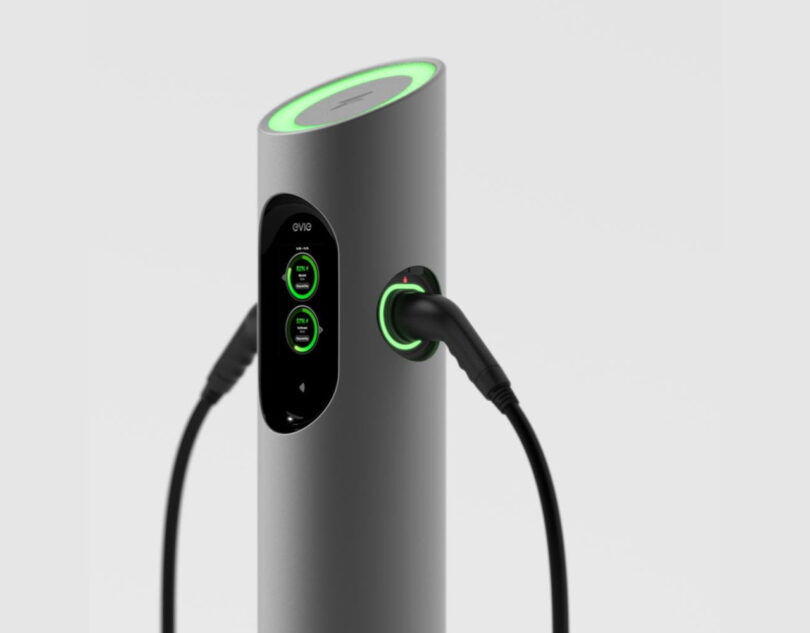 Smaller EVIE Mini charging station with dual chargers and shortened pole design topped with glowing green ring and front facing charger/payment screen.