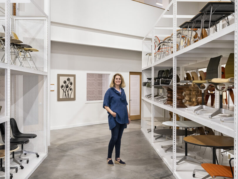 Llisa Demetrios, chief curator and granddaughter of Ray and Charles Eames, standing between shelf displays of Eames designed chairs within the new Eames Archives in Richmond, California