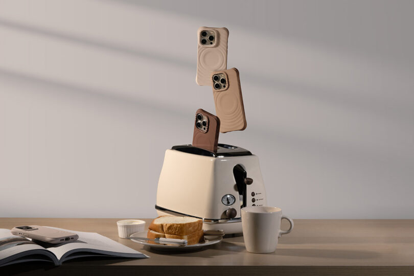 Three iPhones in Essentials by CASETiFYT Ripple staged as if popping out from an oat hued toaster. A plate with bread slices, ramekin of butter, open book with iPhone laid across its open pages, and a coffee cup are set around the toaster.