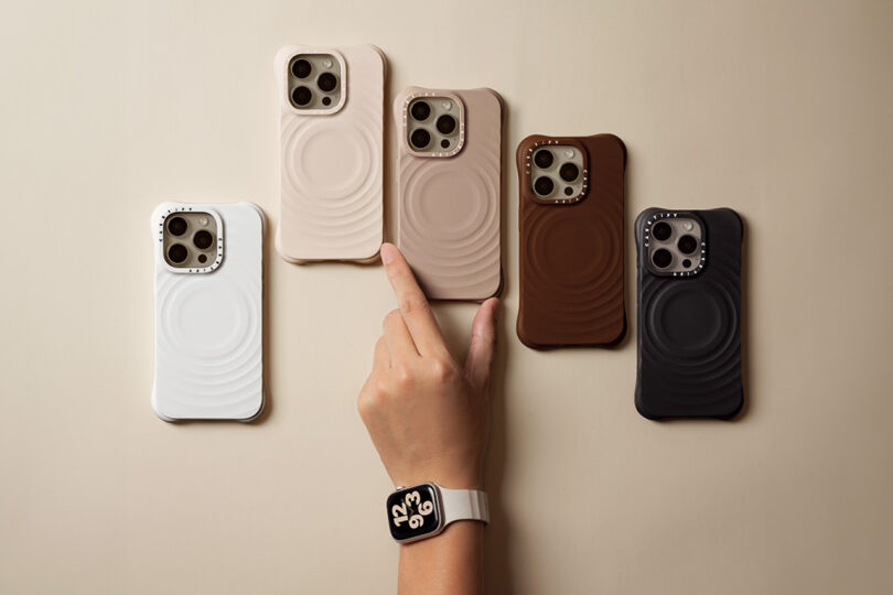 Arm adorned with Apple Watch reaching toward one of five iPhones, each protected by an Essentials by CASETiFYT Ripple. Color order from left to right: White, Oat, Latte, Cacao, and Black.Case,