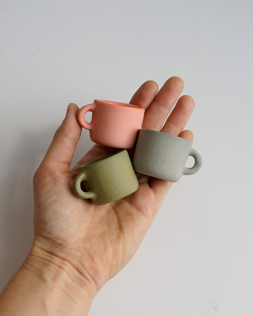hand holding three pastel colored mini mugs