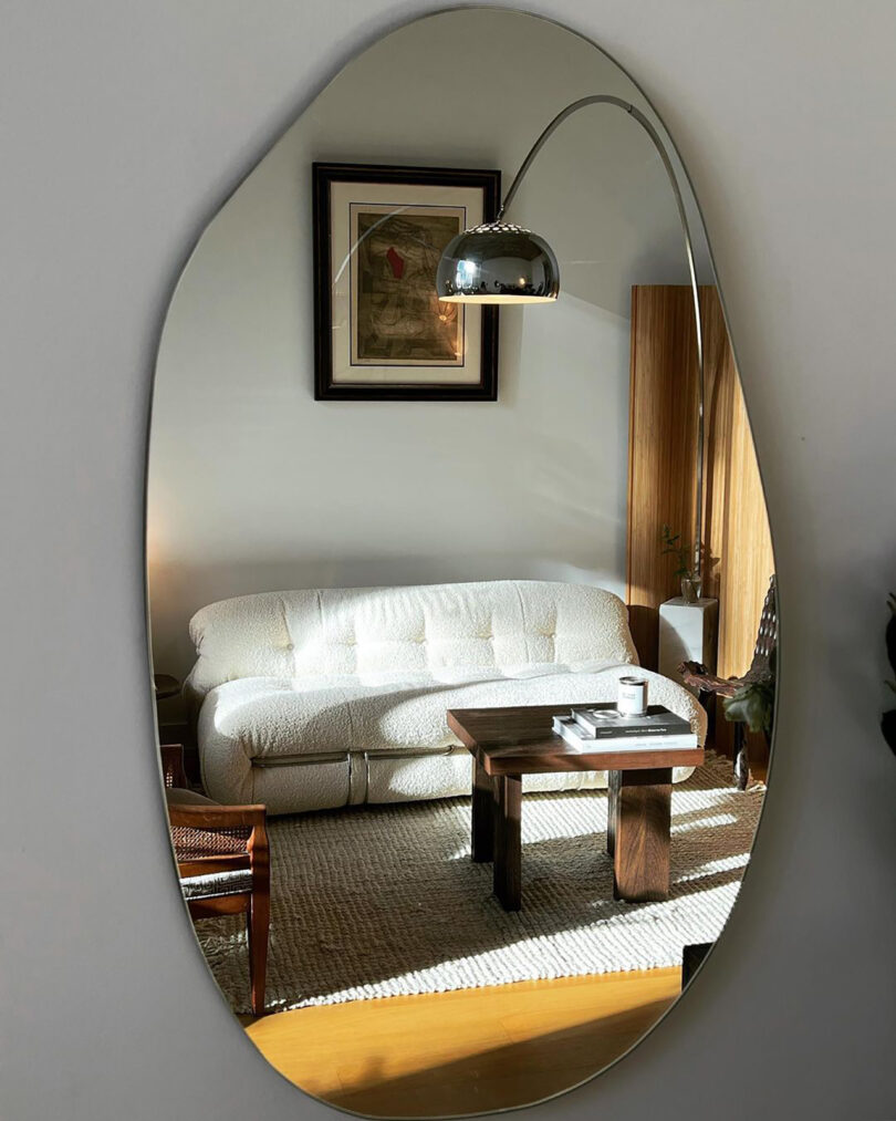 large oval-shaped mirror reflecting a living space