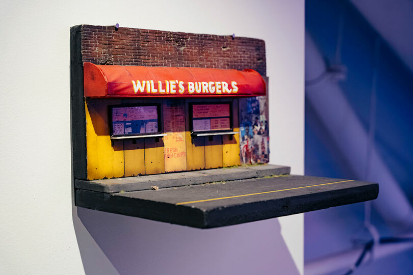 A miniature facade and road of a hamburger joint fixed to the wall.