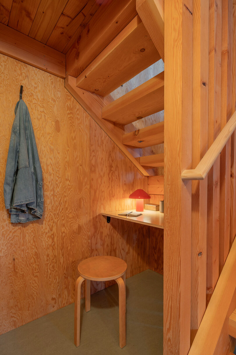 angled interior view of small simple desk under wood stairs in cabin