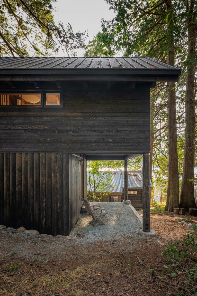 side exterior view of black two-story narrow cabin in woods