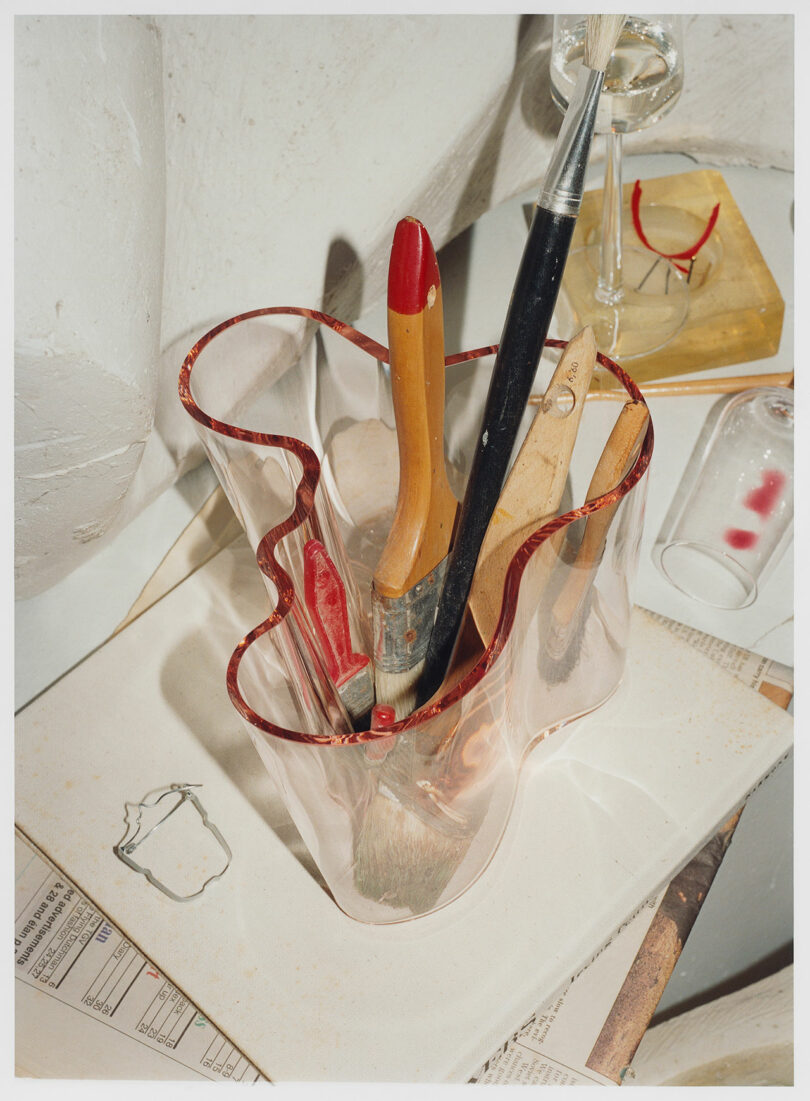 A glass vase with paint brushes in it.