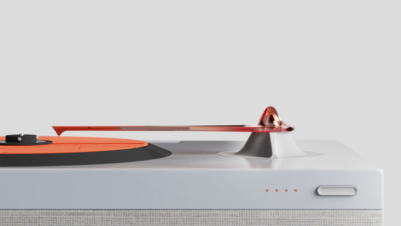 Eye level side view of the Vivia turntable for compact discs, with power button, orange platter top, battery charge indicator and orange clear tone arm prominently in view.