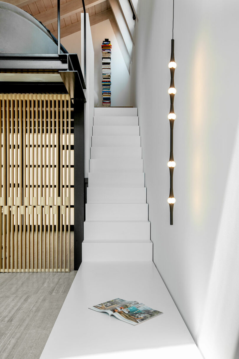 Vista parcial de la moderna sala de estar con estrechas escaleras blancas que conducen al loft