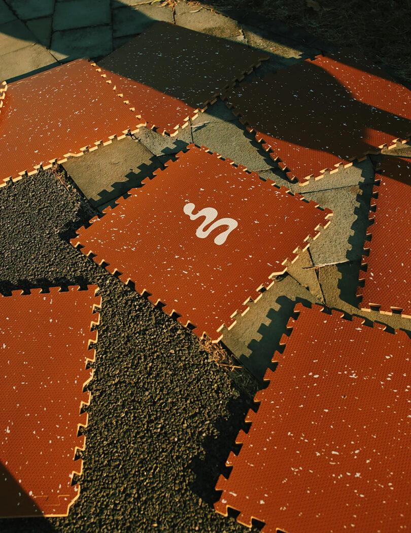 رنگ خاکی نه تکه 72" x 72" تشک کف کف فوم به هم پیوسته پازل جدا شد و یک سطح پوشیده از سنگفرش را در فضای باز به نمایش گذاشت.