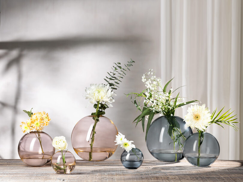 six round pink and blue glass vases with flowers