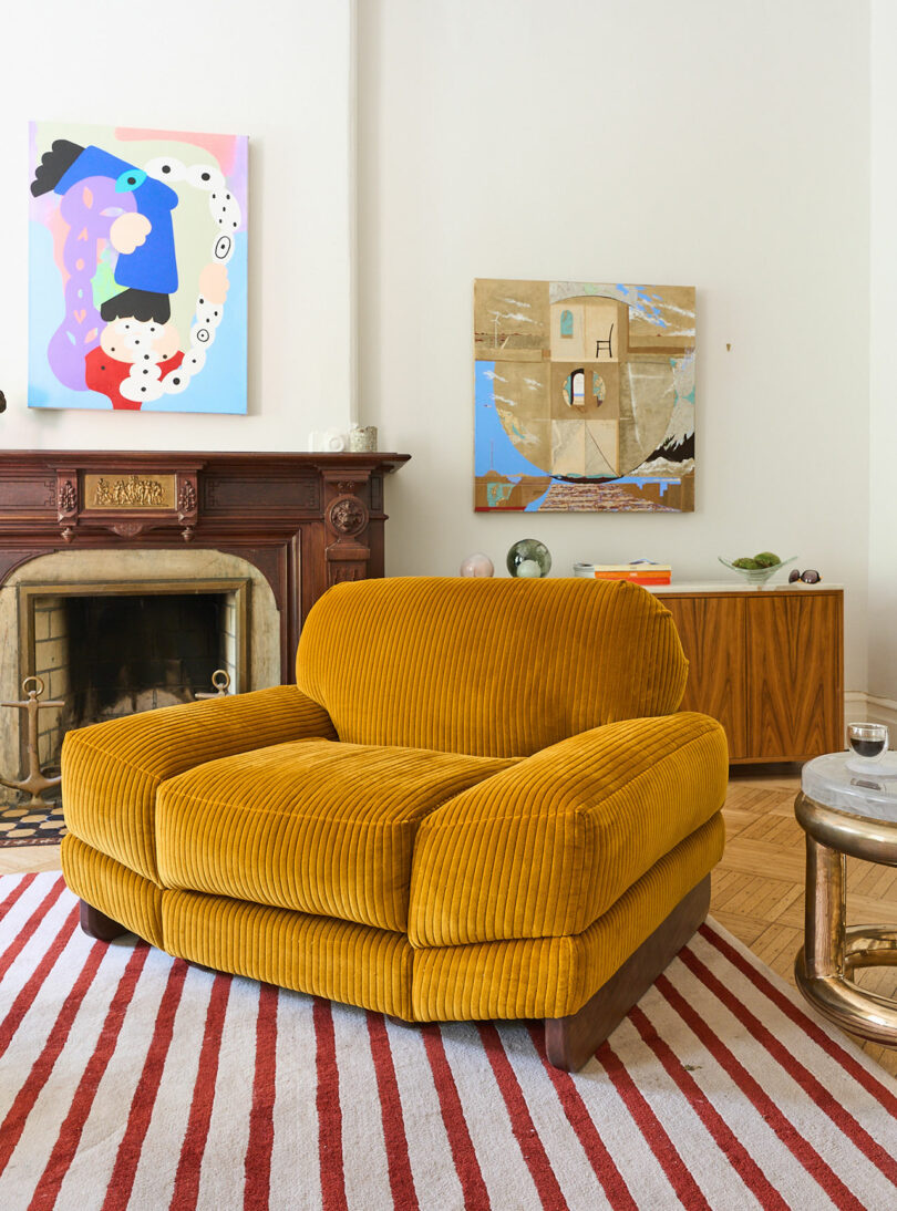 An oversized corduroy lounge chair in a living space in front of a fireplace.