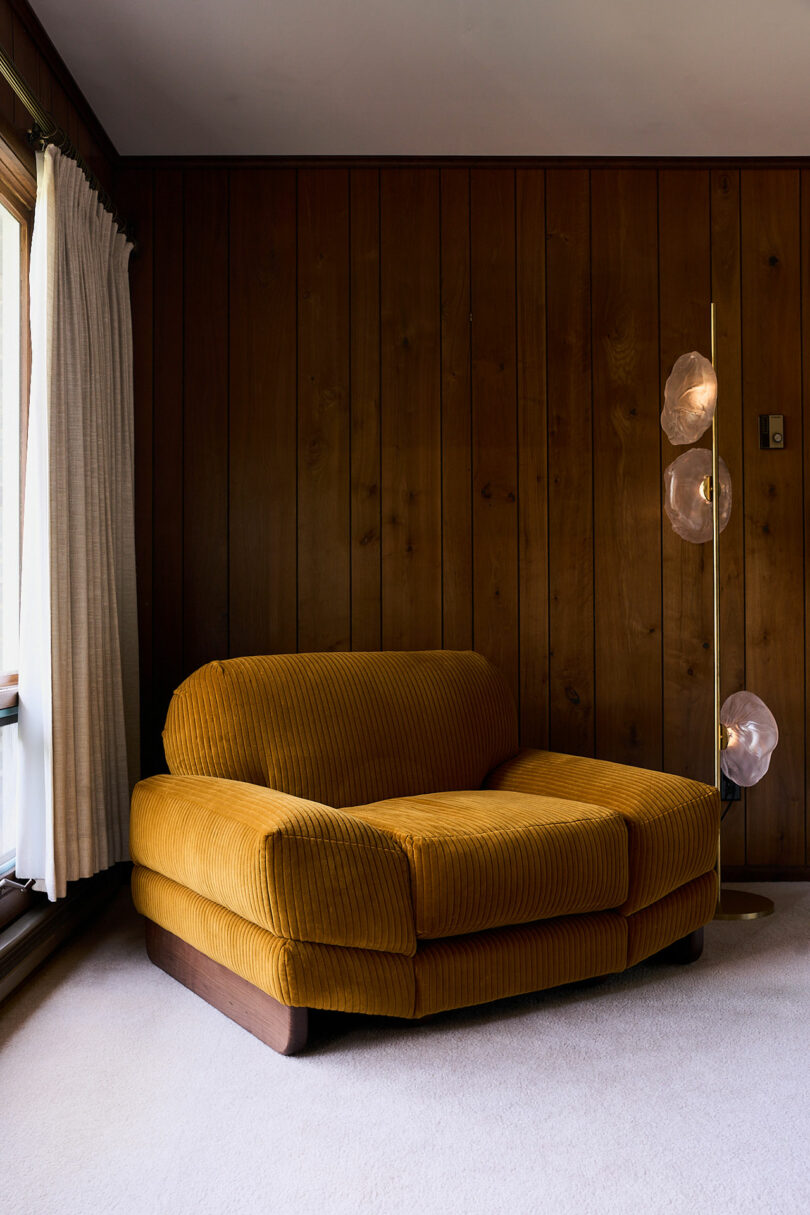 An oversized corduroy lounge chair in a wood paneled room.