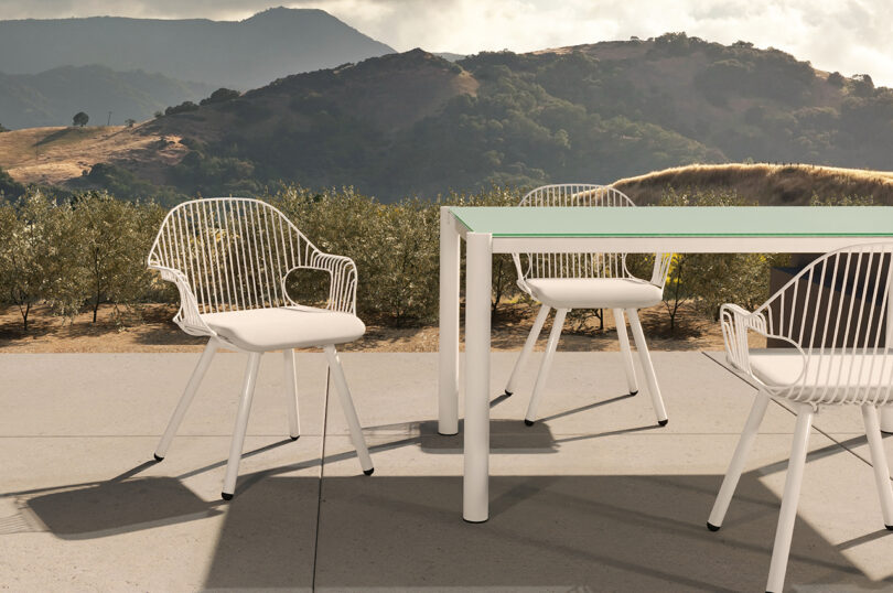 white wire frame outdoor armchairs around an outdoor dining table