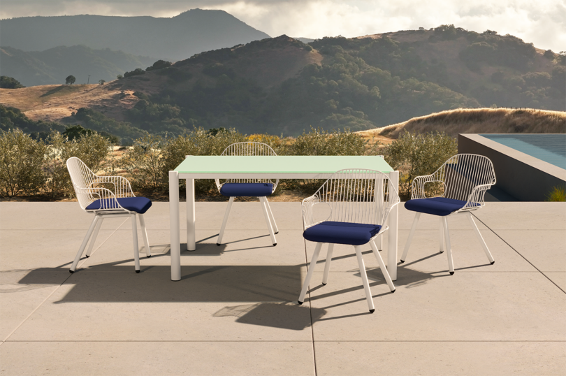 white wire frame outdoor armchairs around an outdoor dining table
