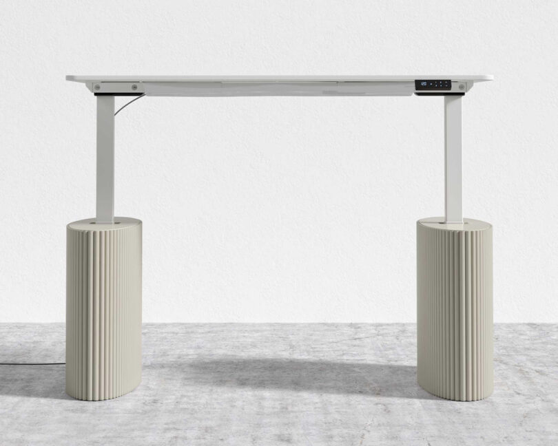 Athena standing desk with fluted alabaster lacquer wood base fully extended to its maximum height of 47.25 inches in standing mode.