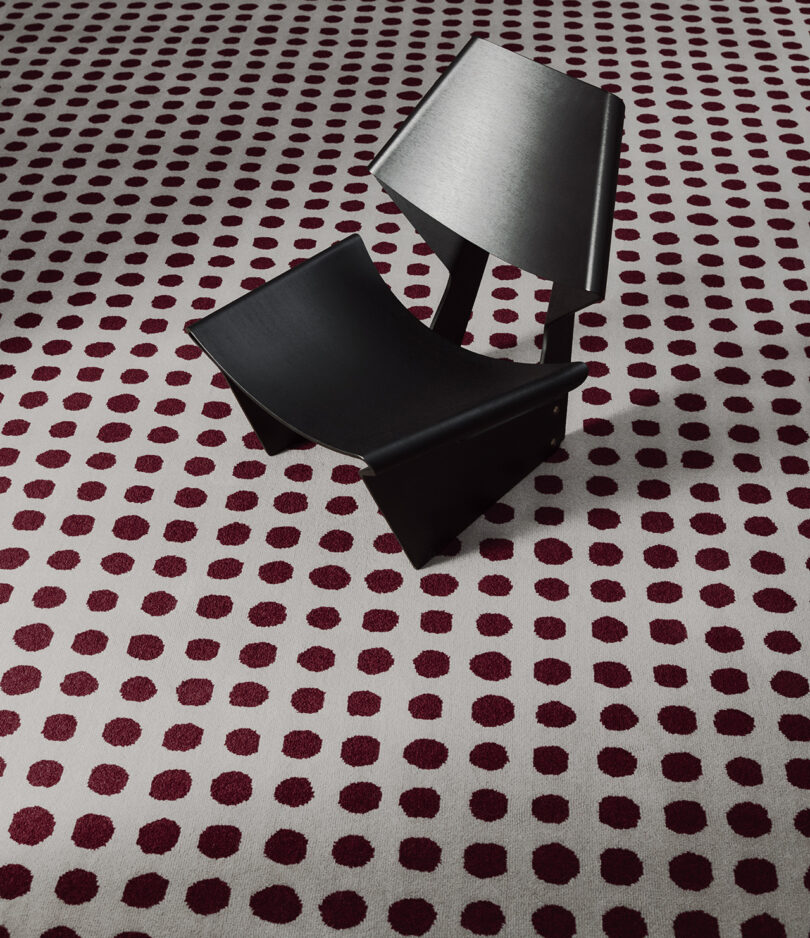 dark red and white dot pattern rug with black modern chair