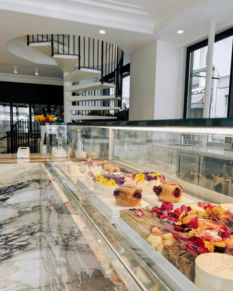 angled interior view of Paris cheese shop with glass display case holding artfully designed cheeses
