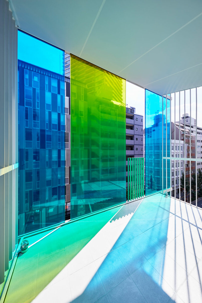 interior view of modern office space looking out to balcony with blue and green exterior glass
