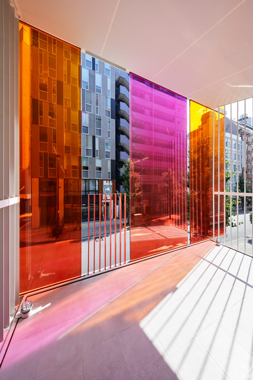 نمای داخلی زاویه دار از فضای اداری مدرن به بالکن با شیشه های بیرونی نارنجی، صورتی و زرد