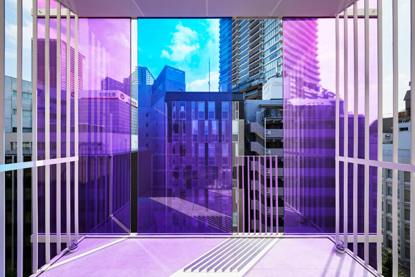 نمای داخلی زاویه دار از فضای اداری مدرن به بالکن با شیشه بیرونی آبی و بنفش