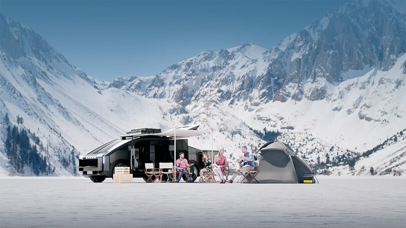 Family camping out in the snow next to 6-wheeled modular EV van concept with futuristic, cyber-mechanical style parked in mountainous landscape with tents and car camping gear.