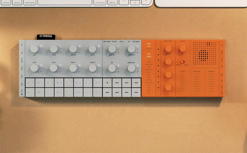 Orange and gray Yamaha SEQTRAK music creation station set across desk surface near Apple keyboard and trackpad.