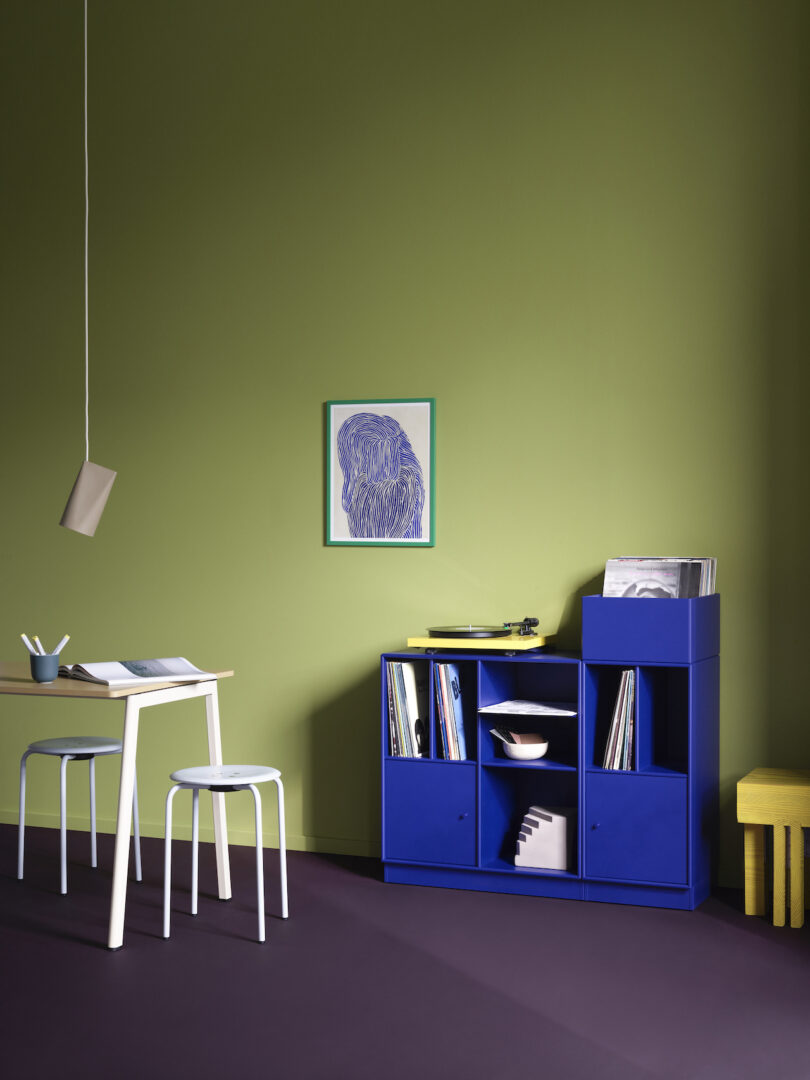 blue vinyl storage furniture holding records and other objects next to a white table and chair