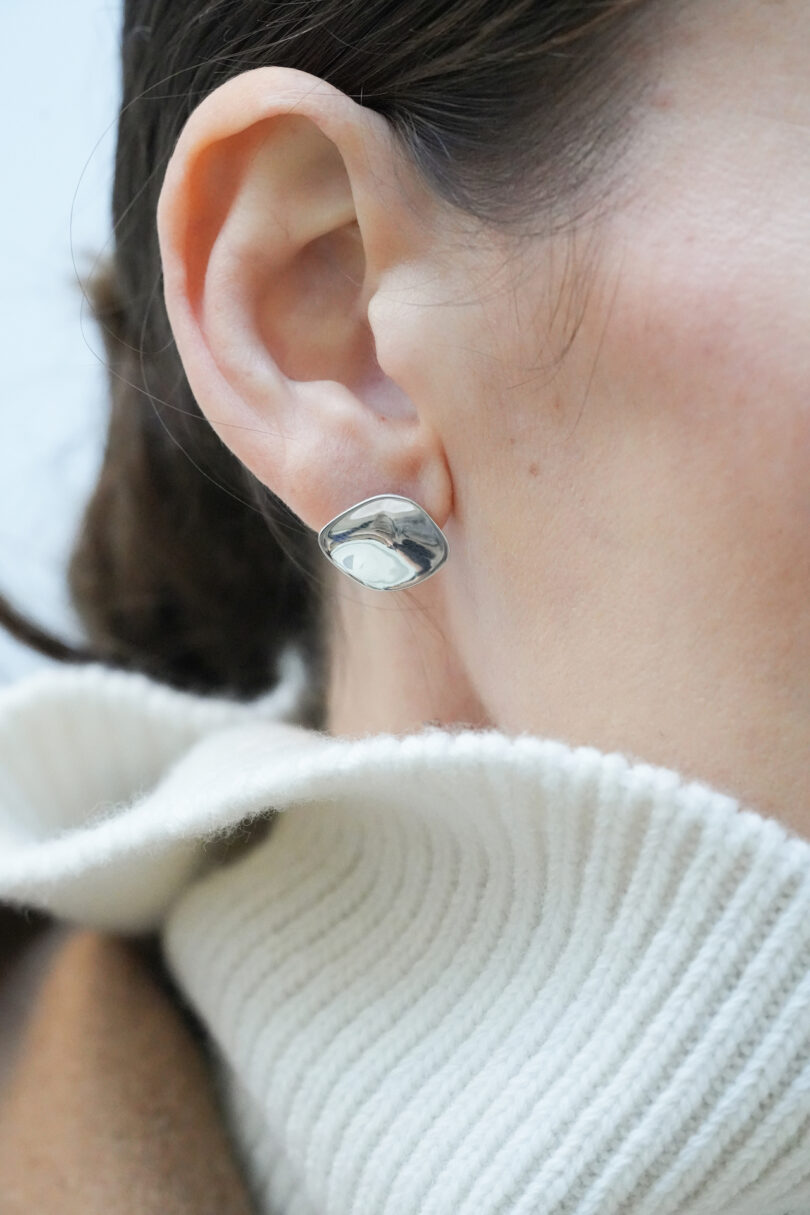 A woman wearing a white sweater and a silver earring