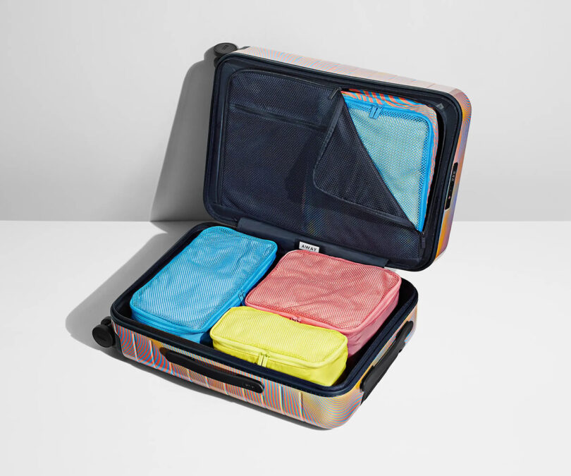 Open luggage with neatly packed colorful AWAY x Resident Advisor Soundwave packing cubes.