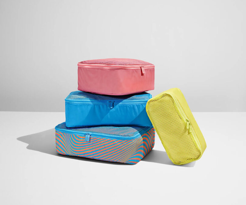 A stack of colorful travel packing cubes on a white background, perfect for organizing luggage.