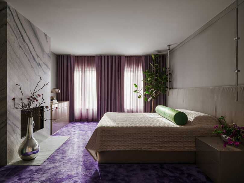 یک اتاق خواب مدرن با روتختی بافت دار، لهجه های بنفش، و نور طبیعی که از پرده های شفاف عبور می کند.