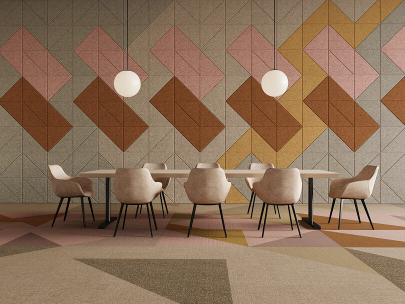 An open space with geometric surface patterns on the floor and wall. There is a table, chairs, and two pendant lights.