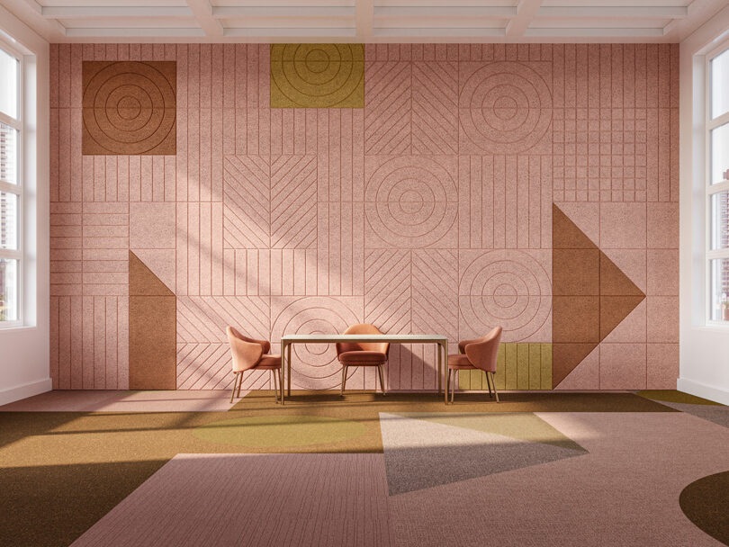 An open space with geometric surface patterns on the floor and wall. There is a table and chairs.