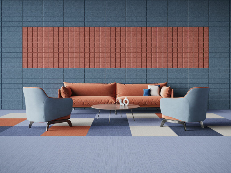 An open space with geometric surface patterns on the floor and wall. There is a table, chairs, and a sofa.