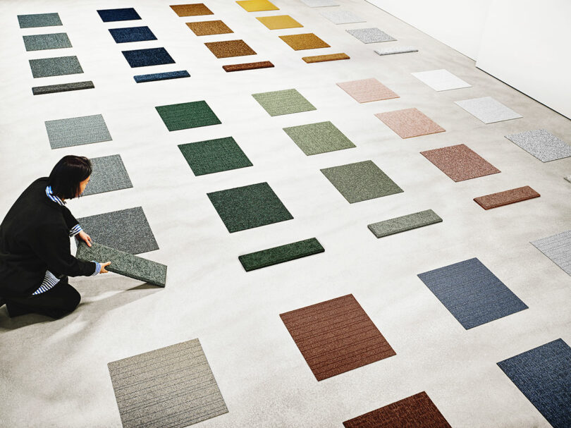 Colorful carpet and wall tile displayed on the floor in a clean, white industrial space.
