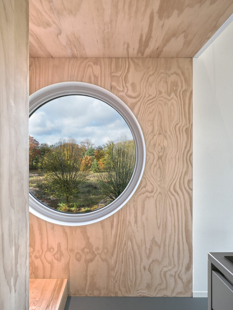 A circular window in a wooden cabin on stilts.