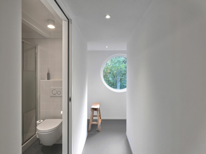 A white bathroom with a round window in small house.