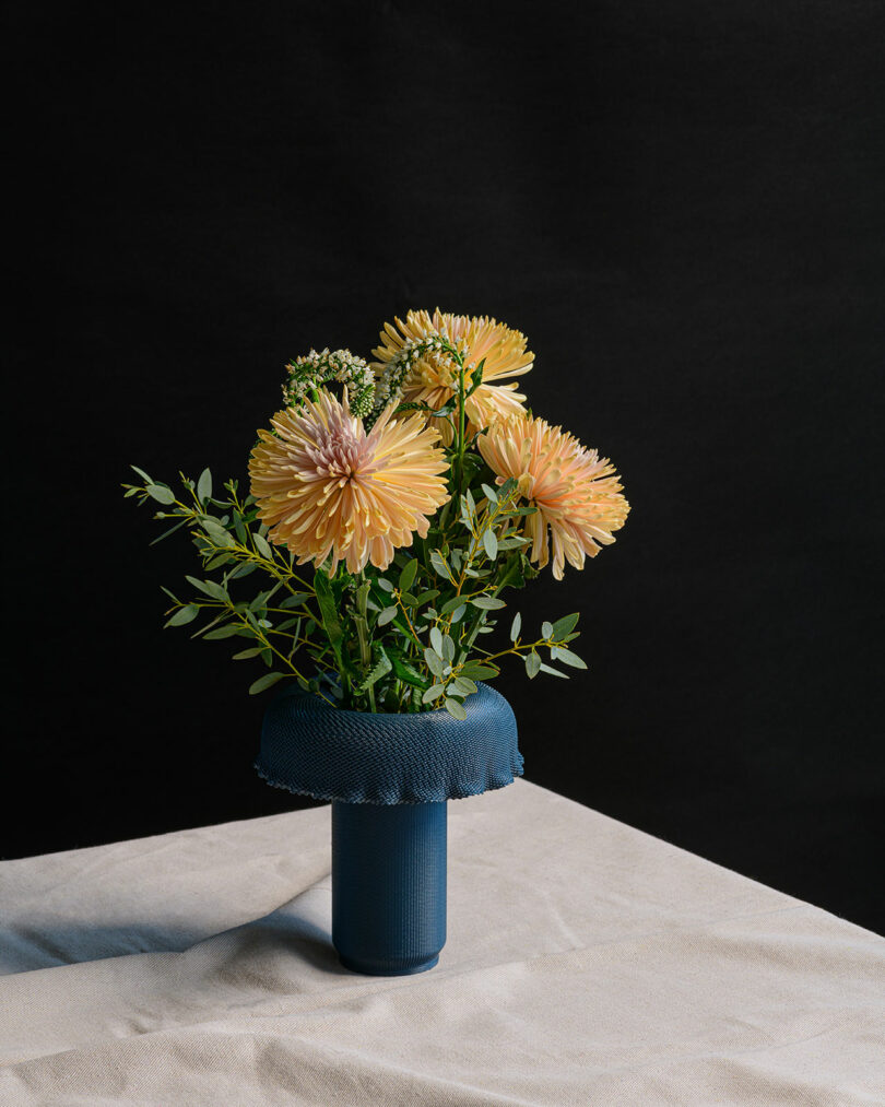 A contemporary, textured vase with flowers in it.