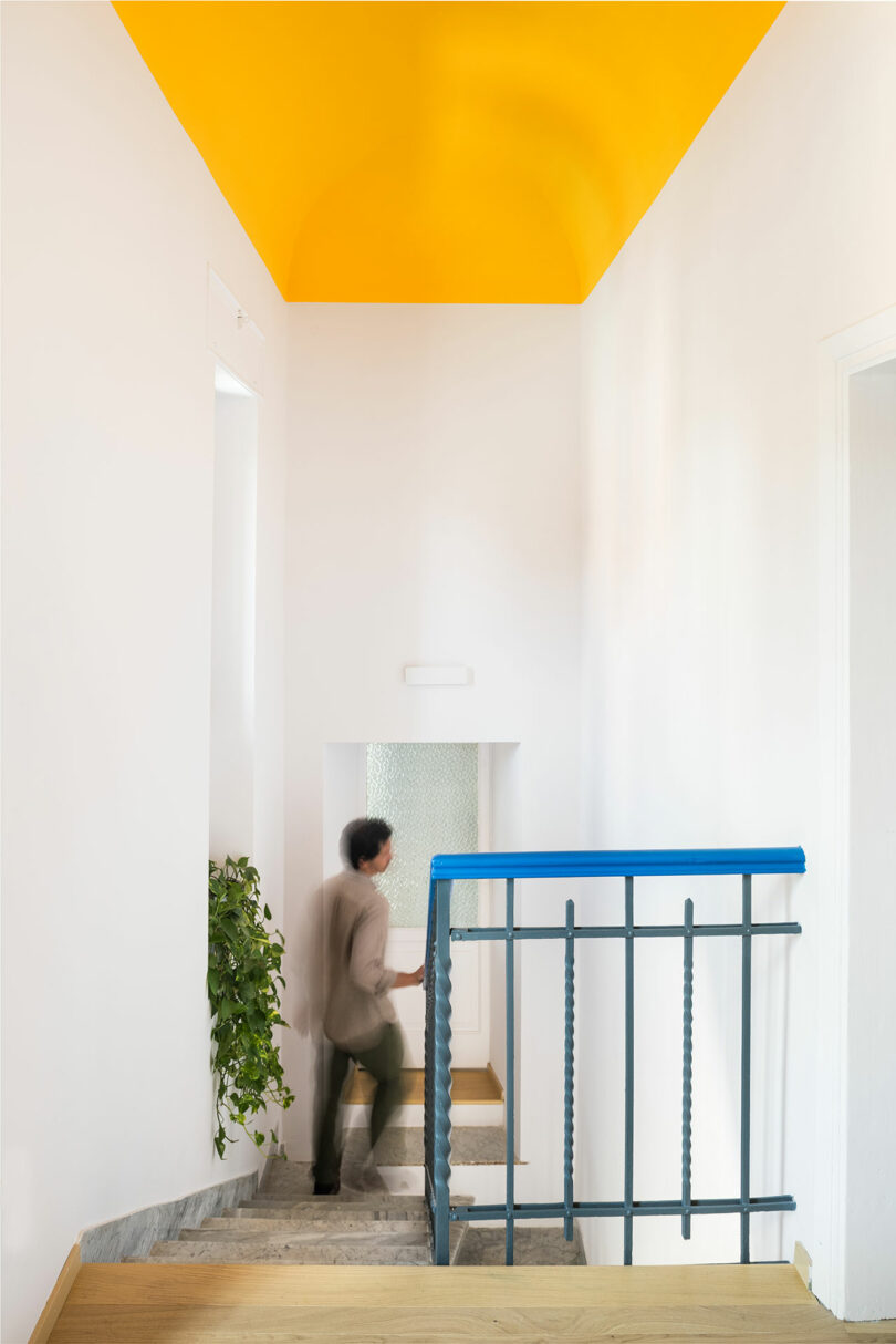man going down staircase under yellow ceiling